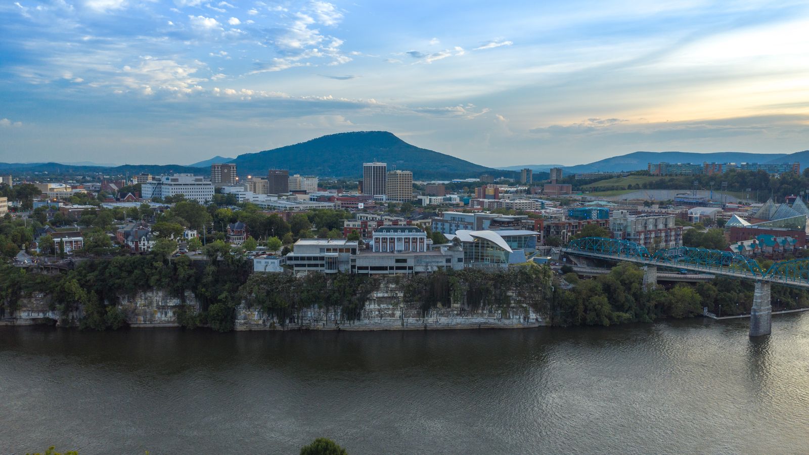 Downtown Chattanooga across the Tennessee River late in the day, with Lookout Mountain behind and the Walnut Street Bridge at the right.