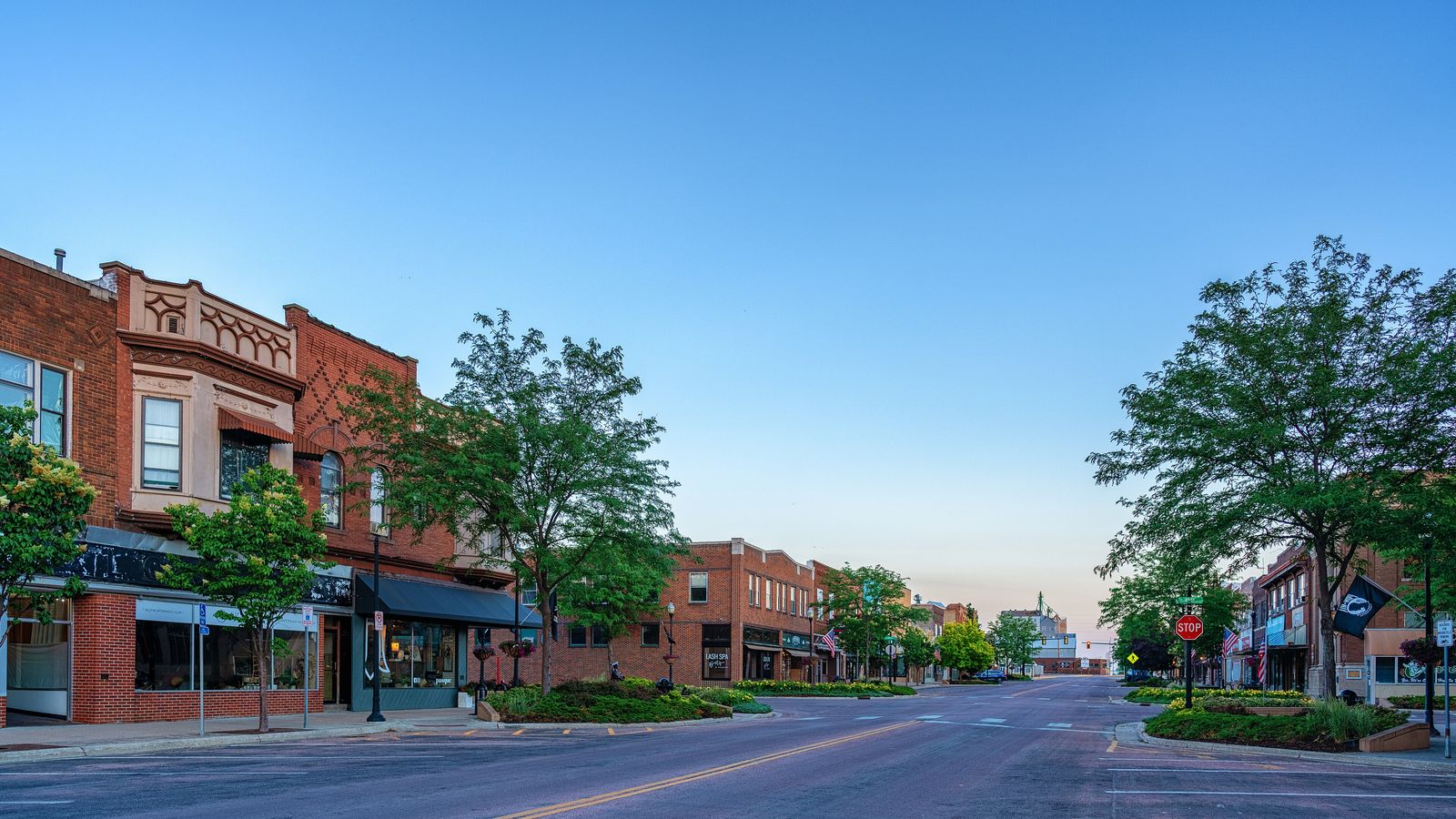 Main Avenue in Brookings at dusk, with brick storefronts and young trees.