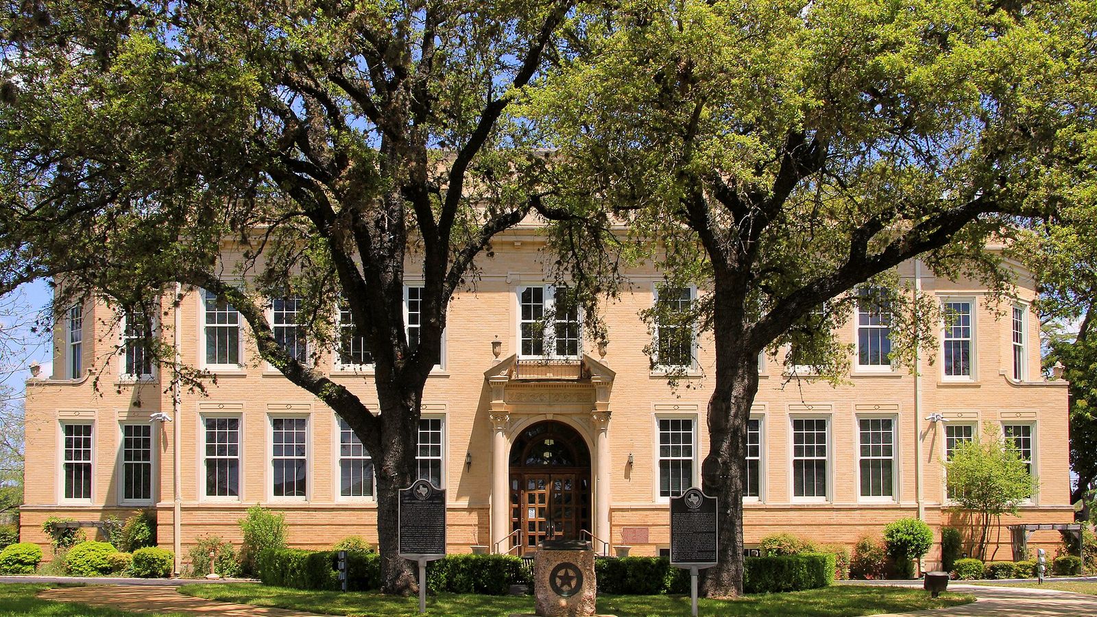 The 1926 Kerr County Courthouse in downtown Kerrville, framed by big live oaks.