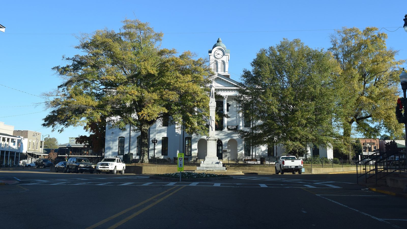 The white Lafayette County Courthouse among big shade trees on the Square in Oxford.